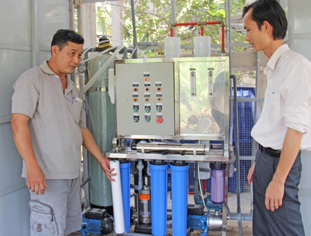 Anh Bạc (trái) giới thiệu hệ thống lọc nước mặn thành ngọt.
