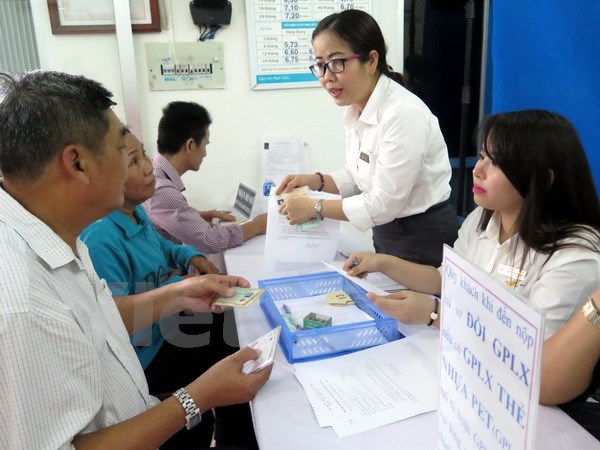 Người dân đến làm thủ tục cấp đổi và nhận giấy phép lái xe tại Bưu điện Bình Chánh. (Ảnh: Hoàng Hải/Vietnam+)