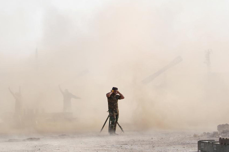 Một chiến binh Shiite bịt tai lúc khẩu pháo gầm vang giội bão lửa lên đầu IS gần Fallujah.