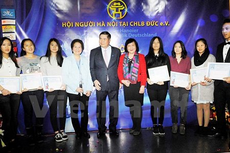 Đại sứ Đoàn Xuân Hưng trao giấy khen cho các học sinh có thành tích học tập tốt. (Ảnh: Mạnh Hùng/Vietnam+)