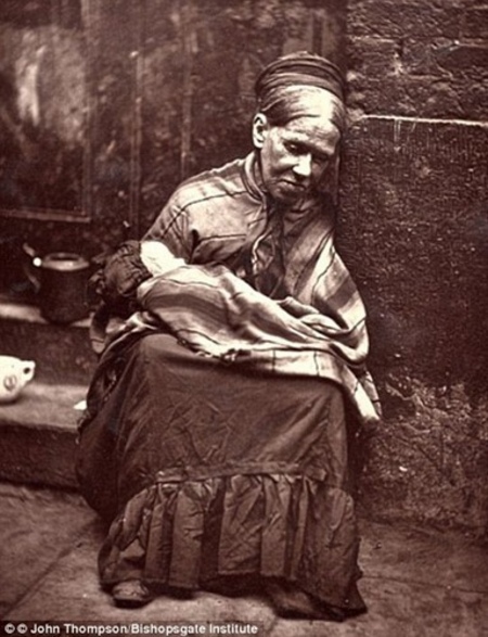 Một người phụ nữ già nua mệt mỏi ngồi bên vệ đường. (ảnh: Bishopsgate Institute).
