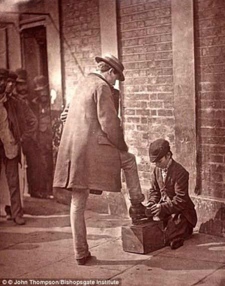Một cậu bé đánh giày chăm chỉ làm công việc của mình. (ảnh: Bishopsgate Institute).