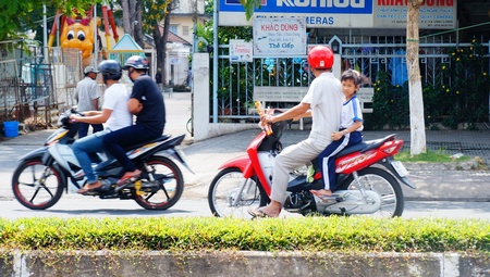 Khi chở trẻ bằng xe máy, cha mẹ nên đội nón bảo hiểm để bảo vệ an toàn cho con.