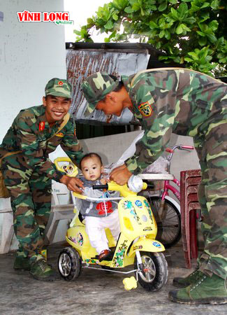 Hai chiến sĩ trẻ đảo Thổ Chu đùa vui với em bé trên đường công tác.