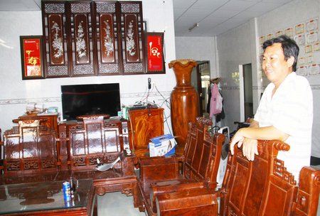 Anh Ngô Tấn Lộc bên bộ bàn ghế bằng gỗ ghiến, cũng đã nổi nu rất hiếm thấy.