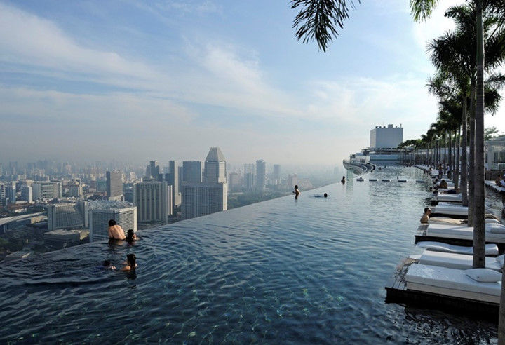Bể bơi vô cực khách sạn Marina Bay Sands, Singapore. (Ảnh: CNTraveler)  Nằm ở tầng cao nhất của khách sạn Marina Bay Sands nổi tiếng với độ cao gần 200m, bể bơi này là niềm mơ ước của những tín đồ yêu thích bơi lội. Du khách có thể vừa tắm nắng vừa nhìn ngắm toàn cảnh đảo quốc Singapore. Điểm đặc sắc nhất của bể bơi này chính là toàn bộ thành bể được bao bọc bởi những tấm kính trong suốt tạo cảm giác nó như một hồ nước khổng lồ trên không.