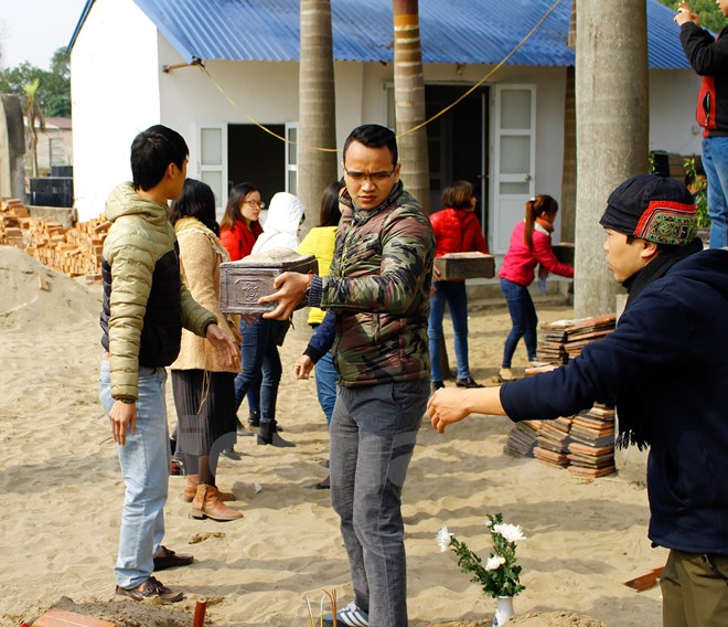 Các tình nguyện viên xếp hàng đưa tiểu về phần mộ để chôn cất. (Ảnh: Huyền Trang/Vietnam+)