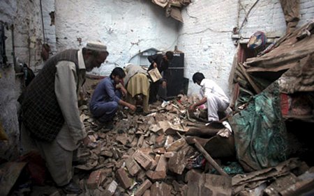 Người dân Afghanistan thu nhặt đồ đạc sau khi căn nhà của họ bị phá nát vì một cuộc tấn công. (Ảnh: AFP)