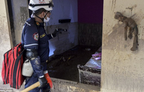 Một lính cứu hộ đi tìm kiếm các nạn nhân trong ngôi nhà ngập bùn đất. Ảnh: Daily Mail/Getty Images.
