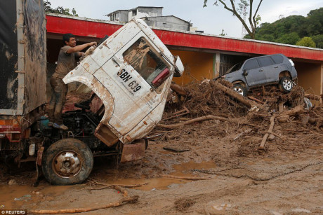 Một chiếc ô tô “ngồi” trên đống cành cây đầy bùn đất ở Mocoa. Ảnh: Reuters.
