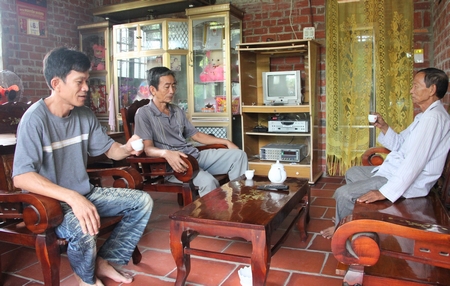 Anh Nguyễn Hoàng Sơn (bìa trái) trò chuyện với chính quyền ấp về chuyện thoát nghèo trong căn nhà đại đoàn kết.