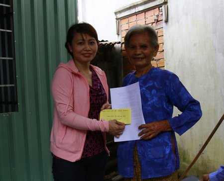 Bà Đỗ Thị Thôi nhận quyết định trao nhà của UBND xã Phú Đức và 1,5 triệu đồng từ Nhóm Vòng tay yêu thương.