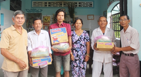 Gia đình ông Phạm Hoàng Huynh (bìa trái) cùng với địa phương tặng quà cho hộ nghèo.