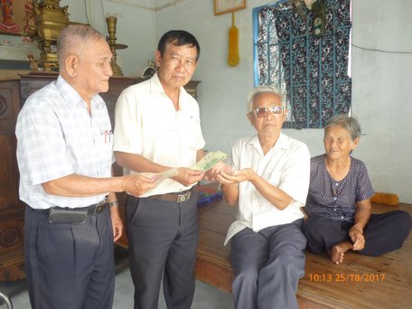 Ông Nguyễn Thành Hổ (trái- ảnh trên) và chú Lê Văn Lai  trao tiền, gạo giúp địa chỉ ở xã Tân An Luông và Tân An Hội.    