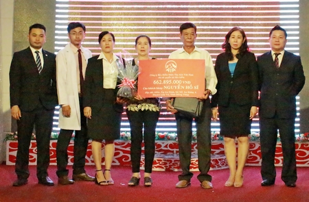 Ông Đỗ Quang Hiển (bìa phải)- Giám đốc Văn phòng Tổng đại lý công ty trao biểu trưng chi trả quyền lợi bảo hiểm cho cha mẹ anh Nguyễn Hồ Sĩ.