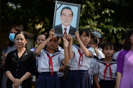 Người dân mang ảnh cố Thủ tướng Phan Văn Khải đứng chờ đón đoàn xe tang của công đi qua trên đường về Củ Chi - Ảnh: THUẬN THẮNG