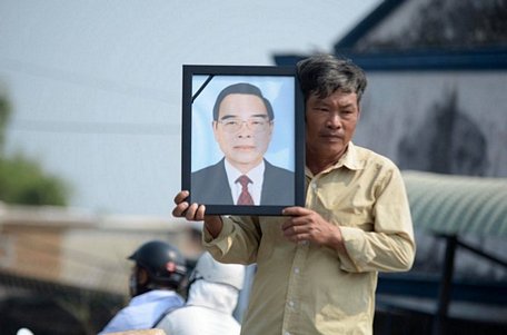 Người dân mang ảnh cố Thủ tướng Phan Văn Khải đứng chờ đón đoàn xe tang của ông đi qua trên đường về Củ Chi - Ảnh: THUẬN THẮNG