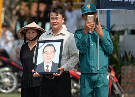 Người dân mang ảnh cố Thủ tướng Phan Văn Khải đứng chờ đón đoàn xe tang của công đi qua trên đường về Củ Chi - Ảnh: THUẬN THẮNG