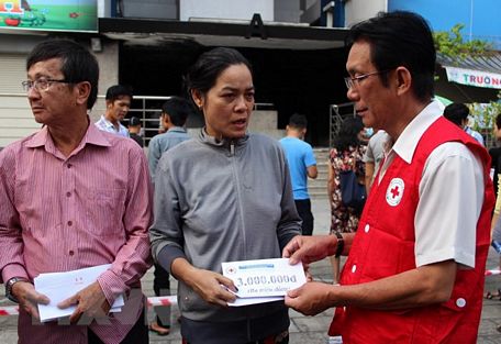 Đại diện Trung ương Hội Chữ thập Đỏ Việt Nam trao hỗ trợ cho gia đình nạn nhân. (Ảnh: Xuân Dự/TTXVN)
