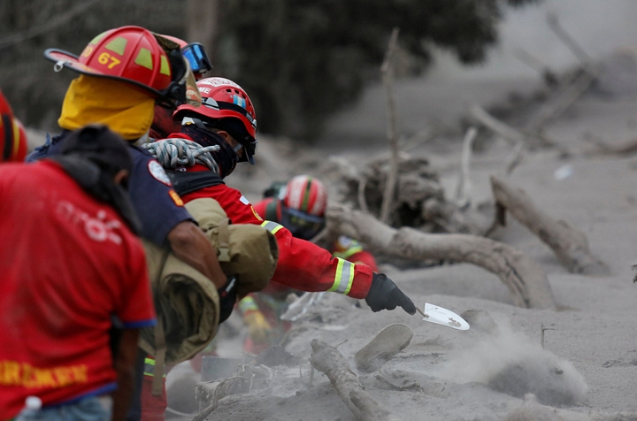 Đội cứu hộ dùng xẻng tay đào bới để tránh va phải thi thể nạn nhân - Ảnh: REUTERS