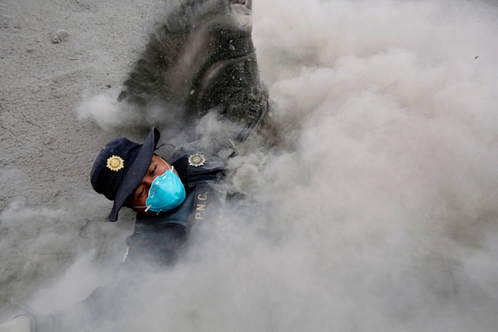 Người lính cảnh sát này trượt ngã khi đang cố gắng chạy trốn bức tường tro núi lửa đang túa ra - Ảnh: REUTERS
