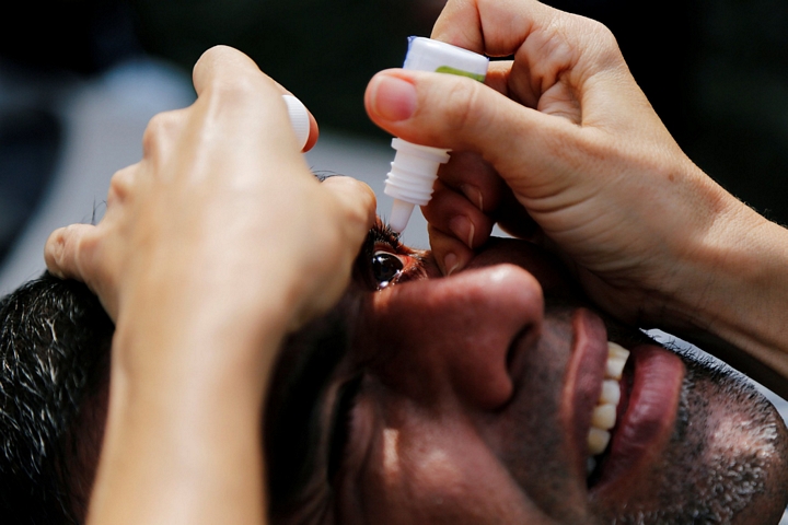 Một người đàn ông được chăm sóc y tế tại trạm xá. Những người tham gia cứu hộ phải liên tục súc mũi, miệng và tra thuốc nhỏ mắt vì tro bụi quá dày đặc - Ảnh: REUTERS