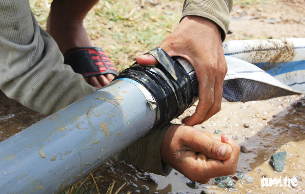 Người dân nối ống nước để bơm nước vào các mảnh ruộng ở xa - Ảnh: DOÃN HÒA