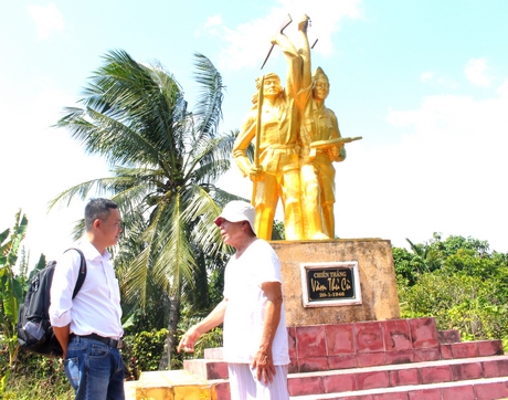 Ông Hồ Tây (phải) bên tượng đài kỷ niệm Chiến thắng vàm Thủ Cù (Tam Bình).
