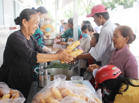 Bà Huỳnh Thị Sương (bìa trái) phát cơm và bánh mì miễn phí cho bệnh nhân nghèo.
