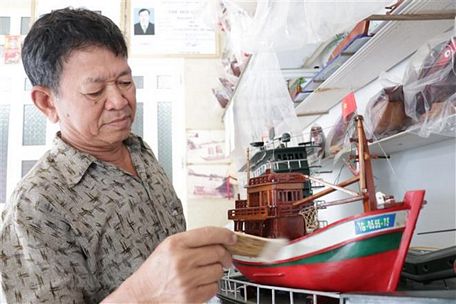 Ông Nguyễn Văn Léo bên sản phẩm tàu biển đánh bắt xa bờ. (Ảnh: Huỳnh Phúc Hậu/TTXVN)