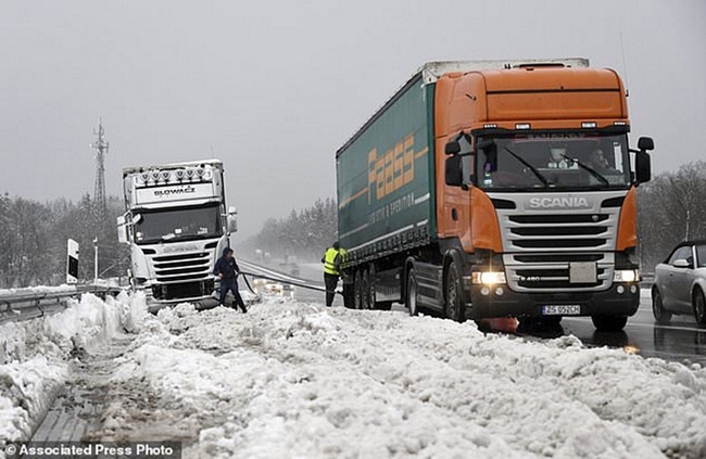 Các tài xế xe tải đang hỗ trợ nhau khi một chiếc xe bị mắc kẹt do tuyết rơi dày ở khu vực Holzkirchen, miền nam nước Đức. Ảnh: AP