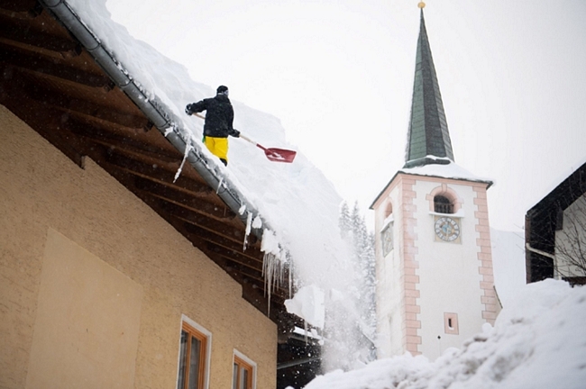 Một người đàn ông dọn tuyết trên mái nhà ở Filzmoos, Áo. Ảnh: Getty