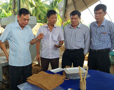 Bí thư Tỉnh ủy Võ Thành Hạo (bìa trái) và đoàn công tác của tỉnh tham quan quy trình sản xuất thảm xơ dừa và tấm gói rau từ xơ dừa của anh Lê Tân Kỳ.