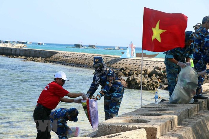 Chiến sỹ Vùng Cảnh sát biển 2 phối hợp với thanh niên tình nguyện dọn vệ sinh môi trường biển tại huyện đảo Lý Sơn, tỉnh Quảng Ngãi. (Ảnh: Trần Tĩnh/TTXVN)