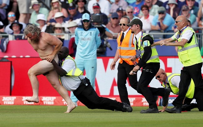 Nhân viên an ninh cố gắng khống chế một người đàn ông “trần như nhộng” chạy vào sân cỏ trong trận đấu thuộc khuôn khổ Giải vô địch cricket thế giới giữa hai đội Anh và New Zealand ở Chester-Le-Street ngày 3/7.