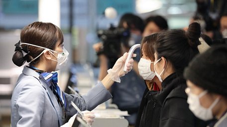 Nhân viên hàng không kiểm tra thân nhiệt các hành khách trước khi họ về Vũ Hán tại sân bay quốc tế Tokyo, Nhật Bản. (Ảnh: THX/TTXVN)