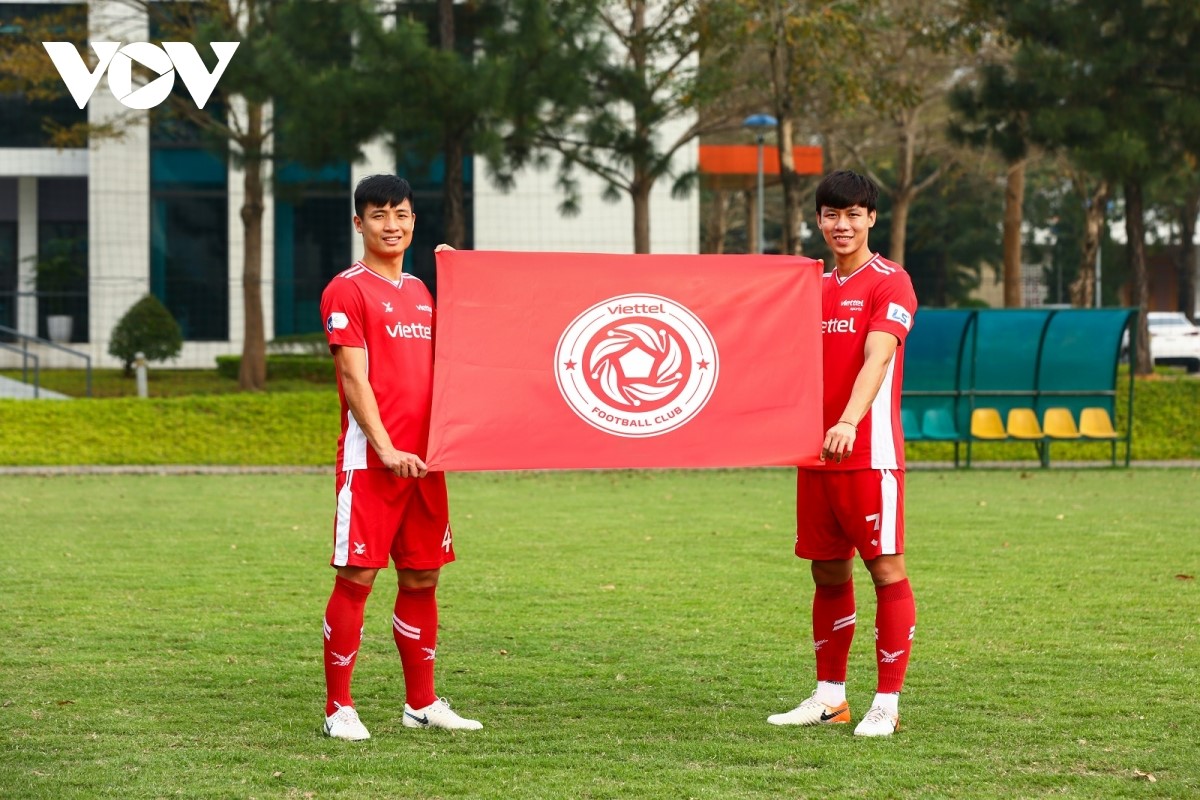 Đội trưởng Bùi Tiến Dũng cùng Quế Ngọc Hải mang cờ với logo mới của Viettel FC.