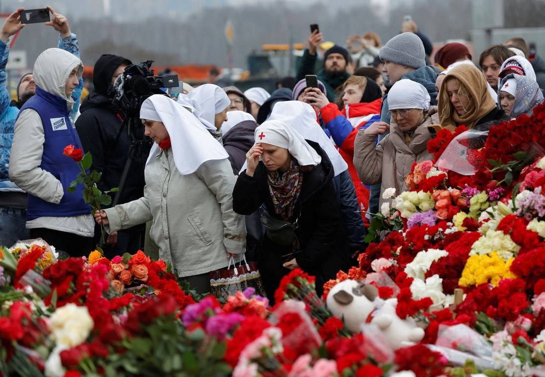Một số nữ tu và người dân đặt hoa tưởng niệm ở khu vực Matxcơva sáng 24/3 - Ảnh: REUTERS