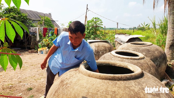 Dù chuẩn bị nhiều lu, khạp chứa nước mưa nhưng ông Lê Văn Thành, xã Hiển Bạch, huyện Thới Bình, tỉnh Cà Mau, vẫn không đủ xài mà phải mua nước từ ghe với giá 50.000 đồng/m3 - Ảnh: THANH HUYỀN