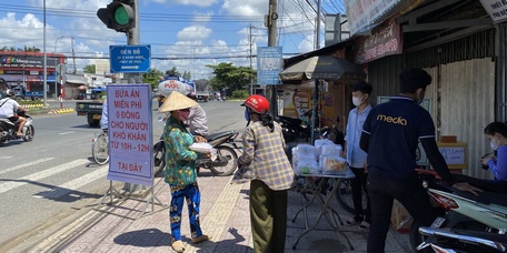 Người bán vé số dạo nhận phần ăn trưa miễn phí tại địa điểm ở Phường 8. Người bán vé số dạo và người lao động tự do khác bị ảnh hưởng nặng nề bởi dịch COVID-19 (ảnh chụp ngày 1/7/2021).