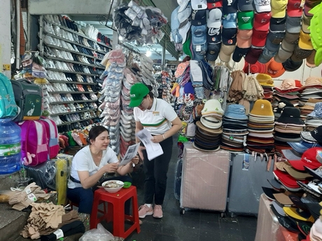 Nhân viên một tổ chức tín dụng trong tỉnh hướng dẫn, hỗ trợ tiểu thương chợ Vĩnh Long sử dụng các tiện ích thanh toán không dùng tiền mặt. Ảnh: TRẦN PHƯỚC